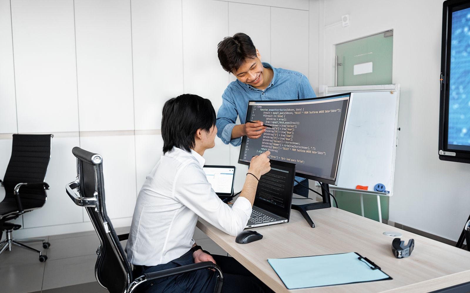 Dos personas revisando código en la pantalla de un puesto de trabajo
