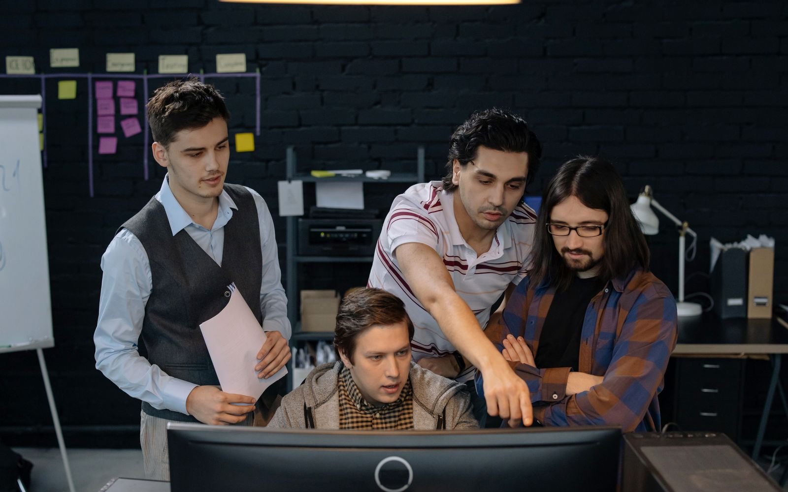 Equipo revisando juntos el trabajo frente a un monitor